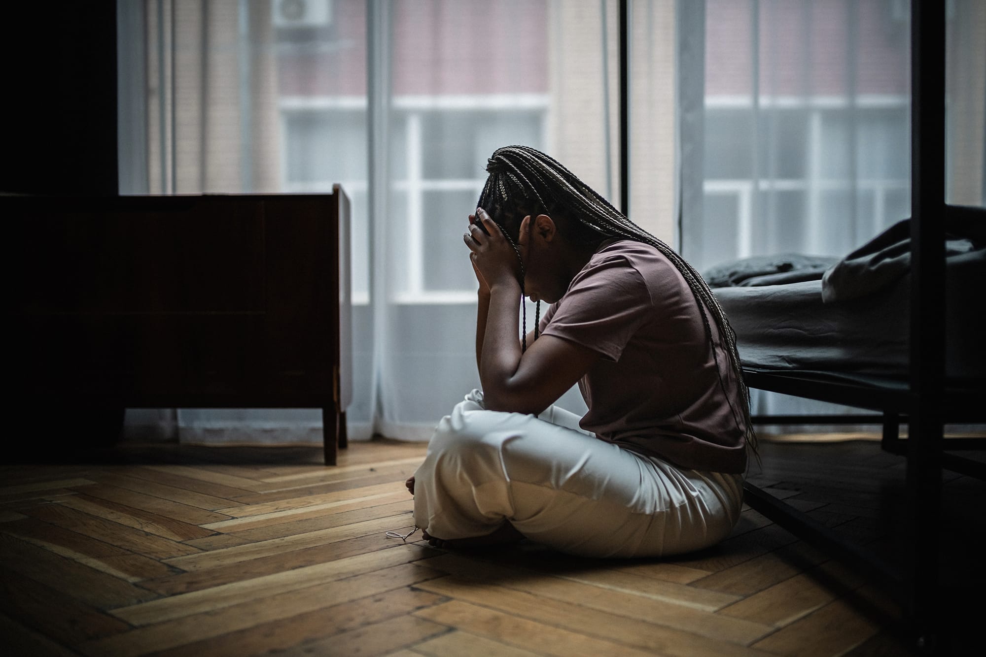 Photo of a woman sitting on the floor with her head in her hands