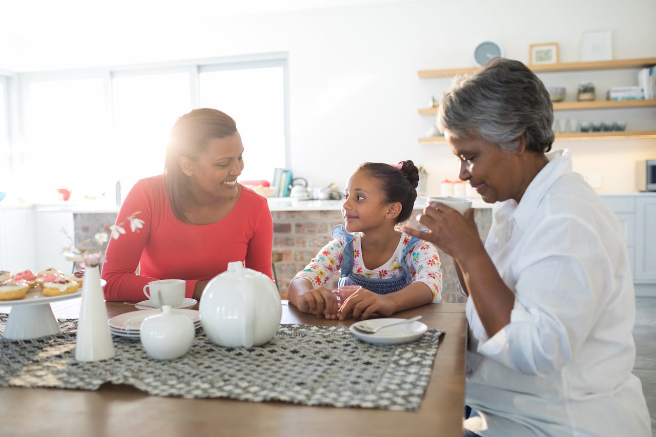 Photo of mother, daughter, and grandmother sitting at a kitchen table.