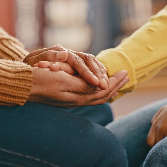 Photo of two people's hands being held in support